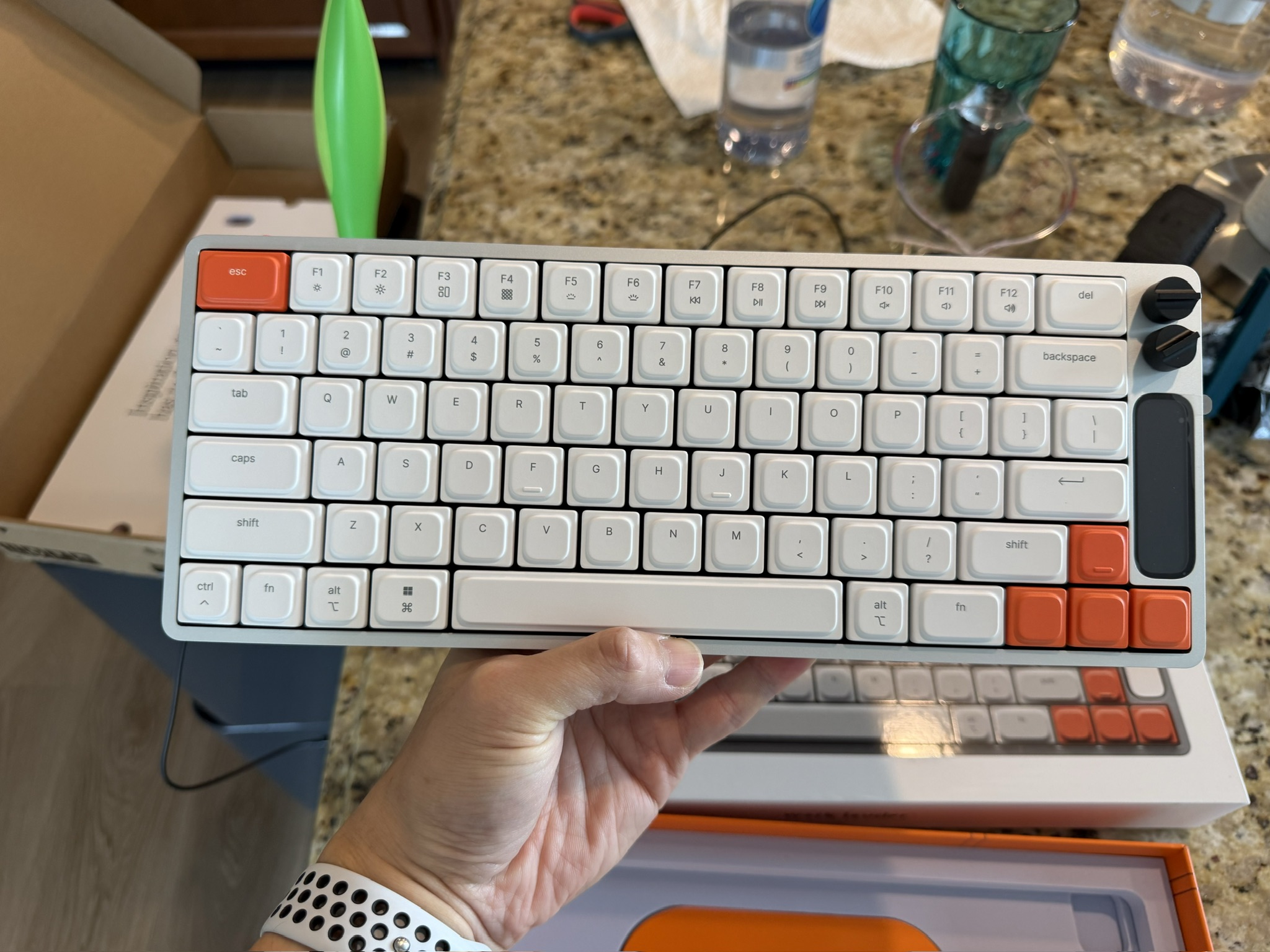 The unboxed Knob Keyboard with white keycaps, orange accents, and two black knobs