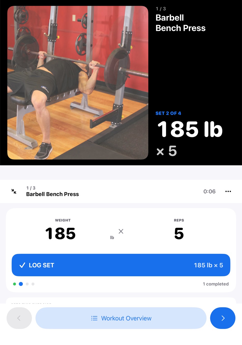 Seated mode while lifting: the bench press demo and Set 2 of 4, 185 lb × 5 in large type on the dark upright half; weight, reps and Log Set on the flat bottom half.